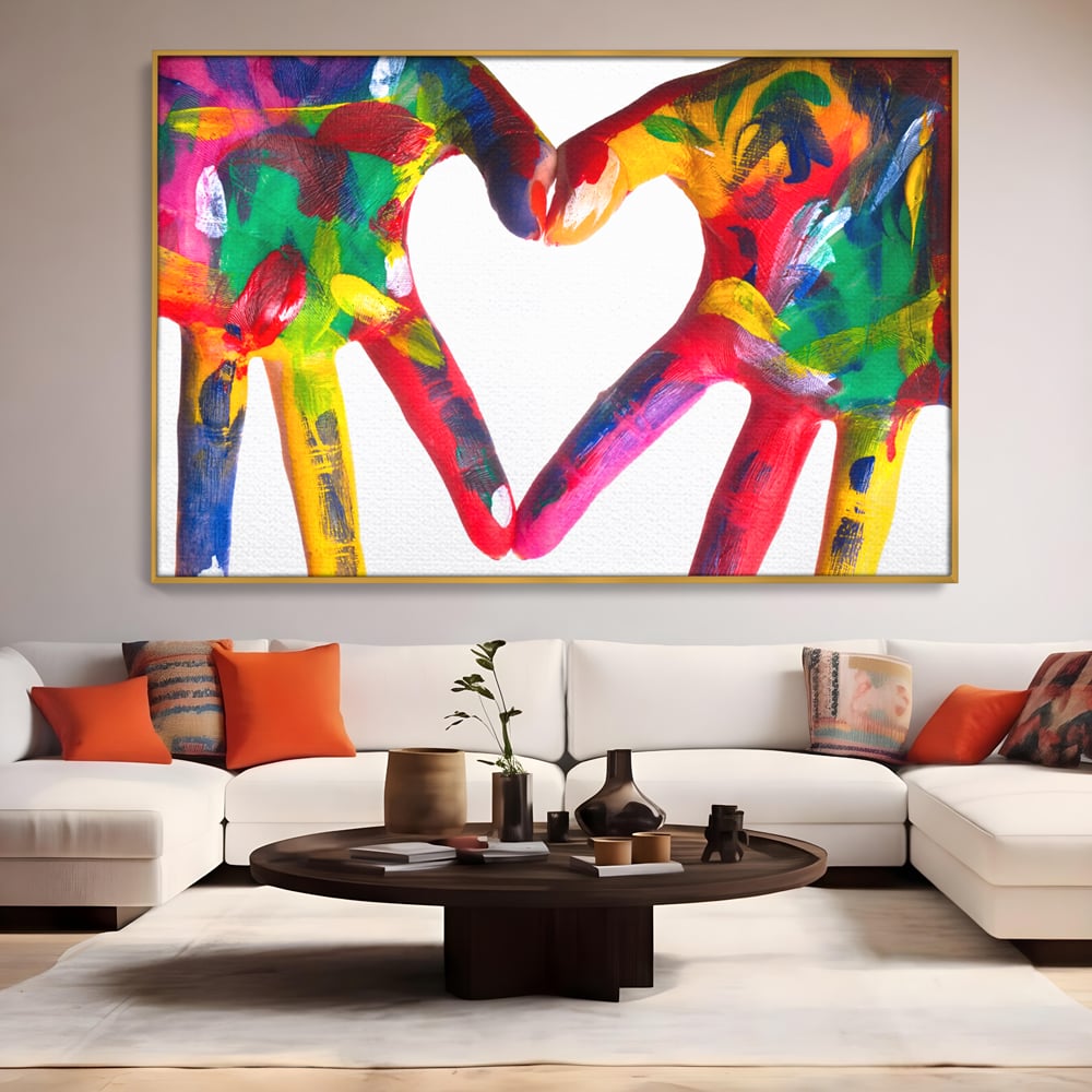Tablou canvas cu pictura cu maini colorate formand o inima, in rama de aluminiu auriu, pe perete intr-un living